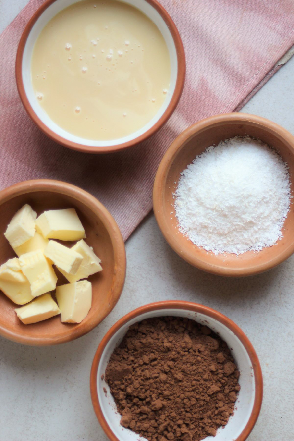 Brigadeiro ingredients a pink napkin on a white surface seen from above.