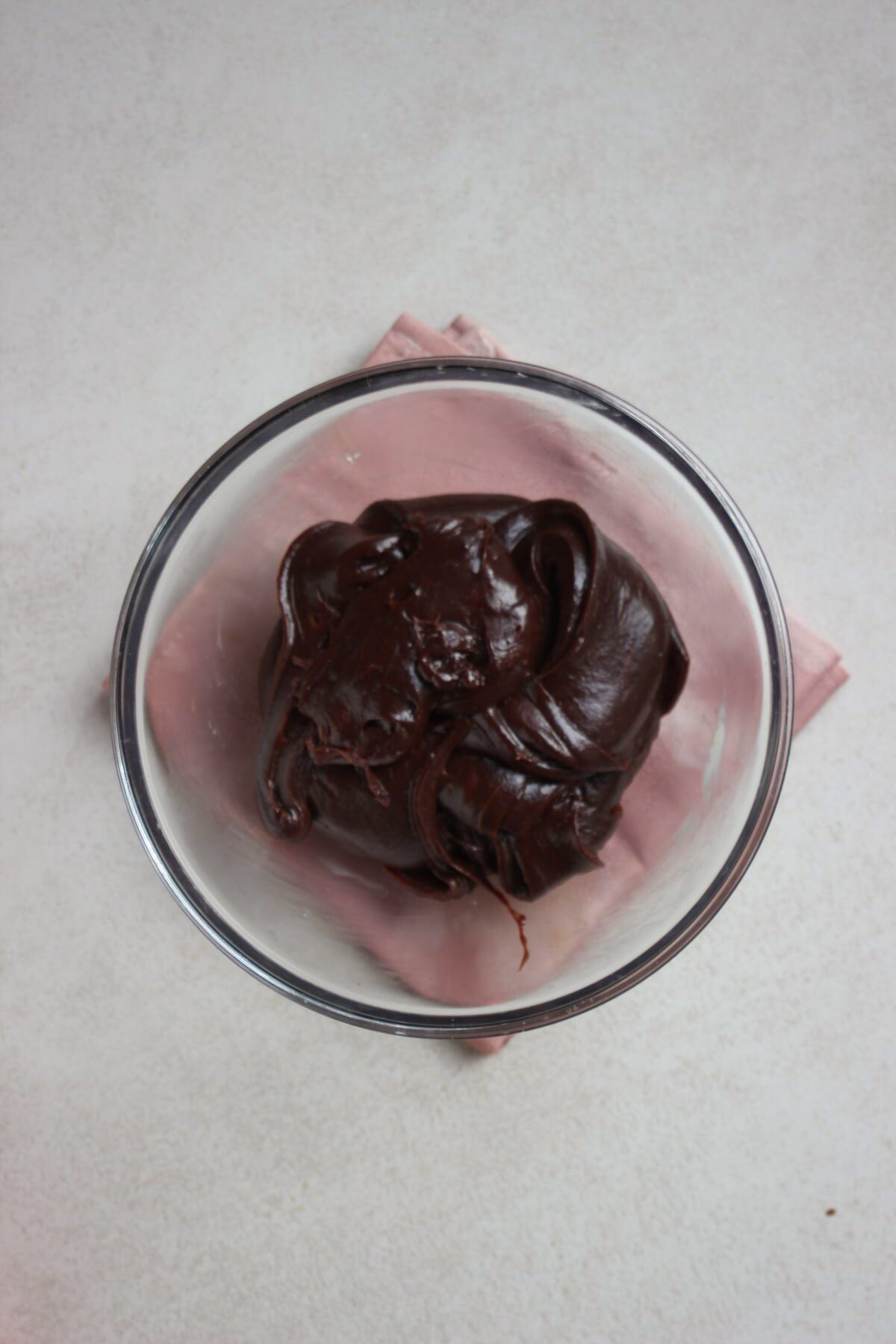 Glass bowl with a chocolate batter. Pink napkin under the bowl.