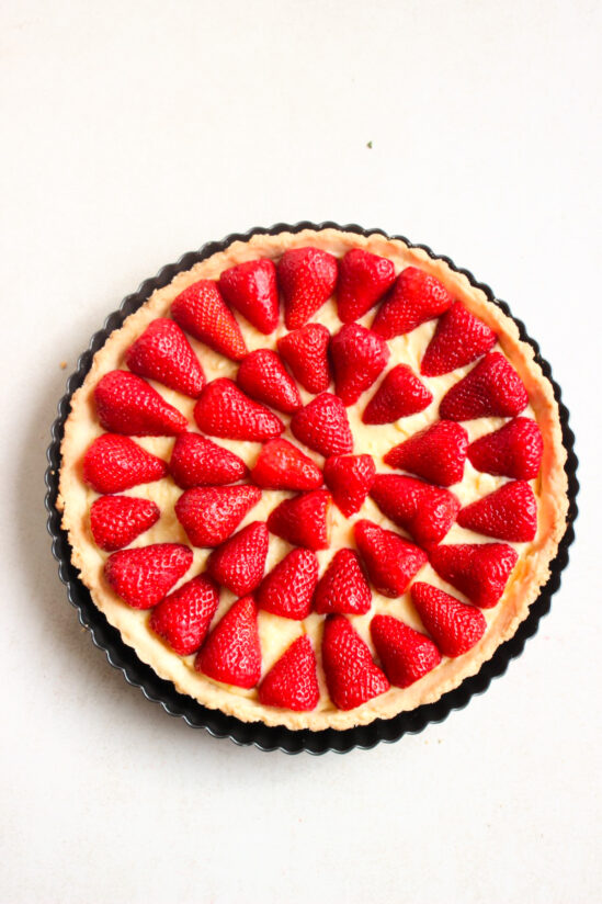 Top view of a strawberry tart in a round tart pan, before baking, and without the strawberry jelly sauce.