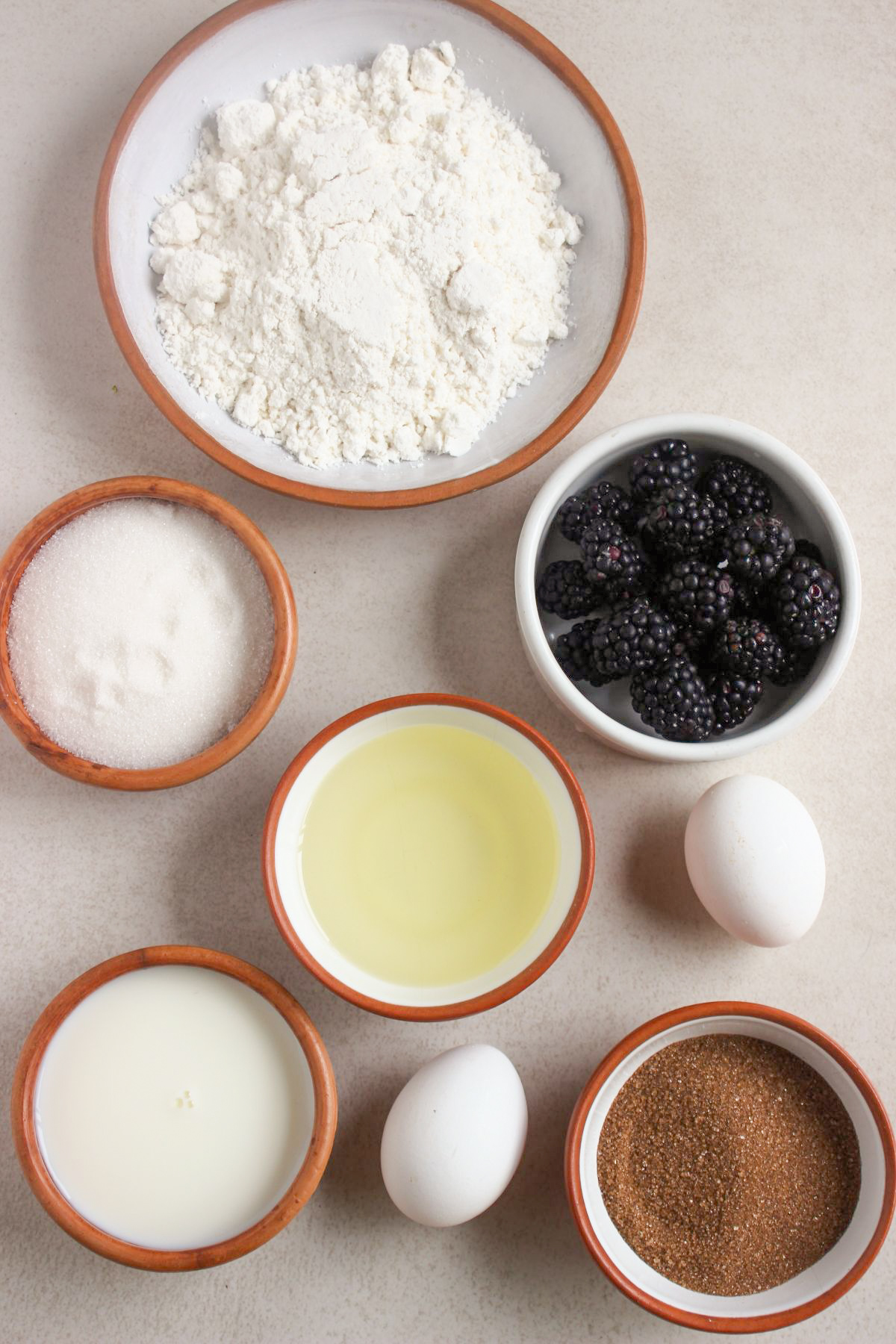 Top view of blackberry muffins ingredients on a white surface.