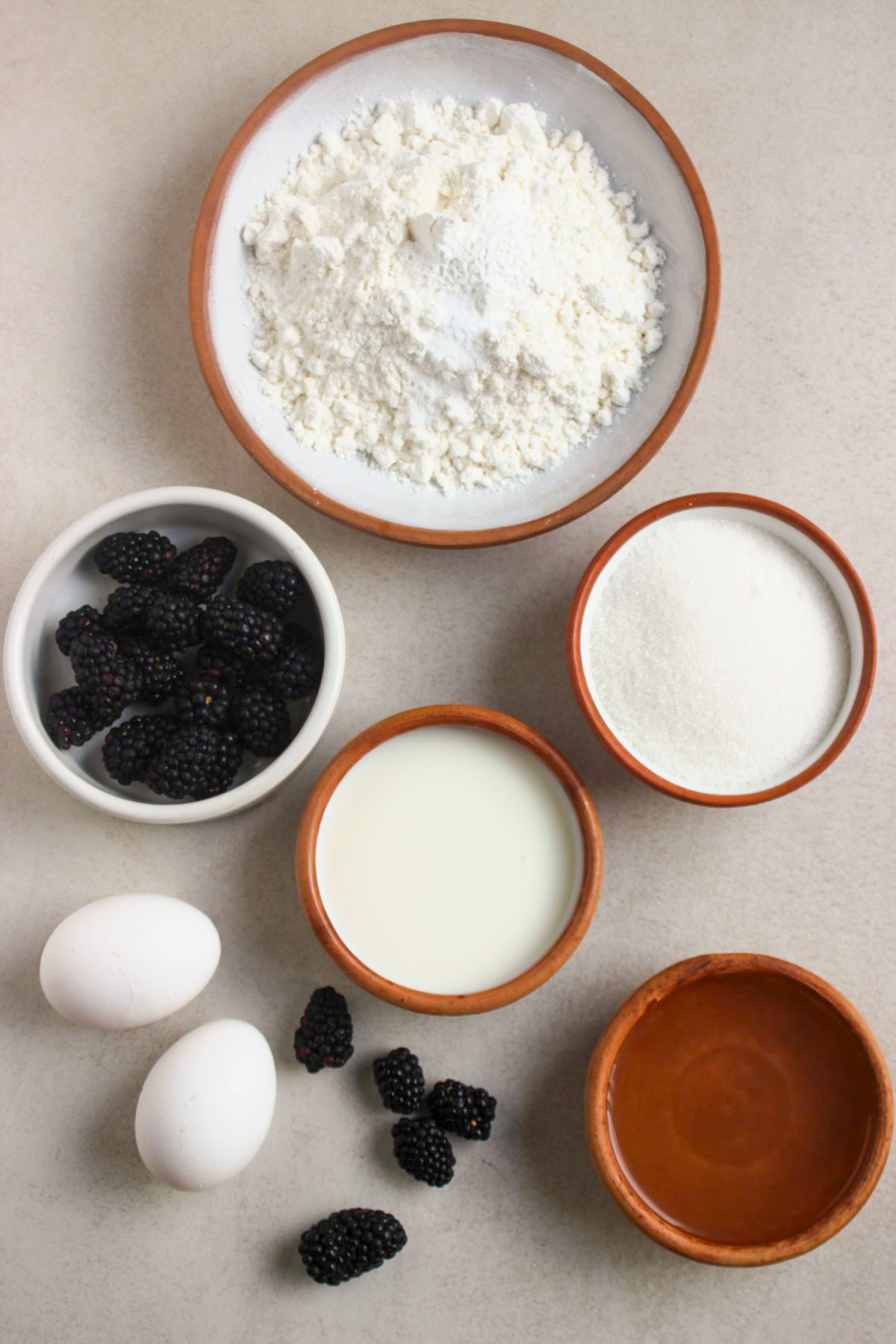 Top view of blackberry cake ingredients on a white surface.