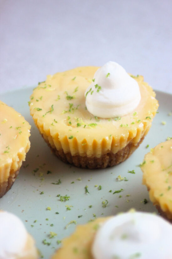 Mini key lime pie with whipped cream on an aqua-green plate.