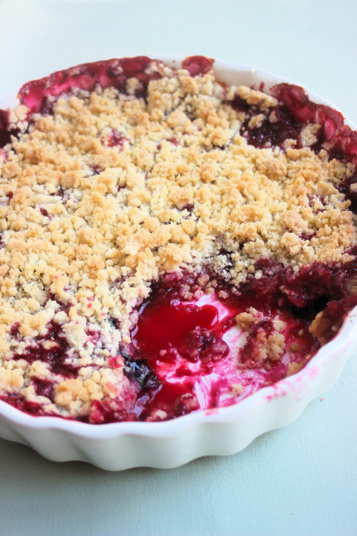 Round baking dish with plum crumble without a portion.