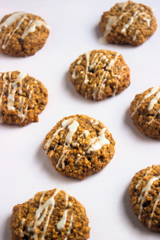 Pumpkin oatmeal cookies iced on white surface.