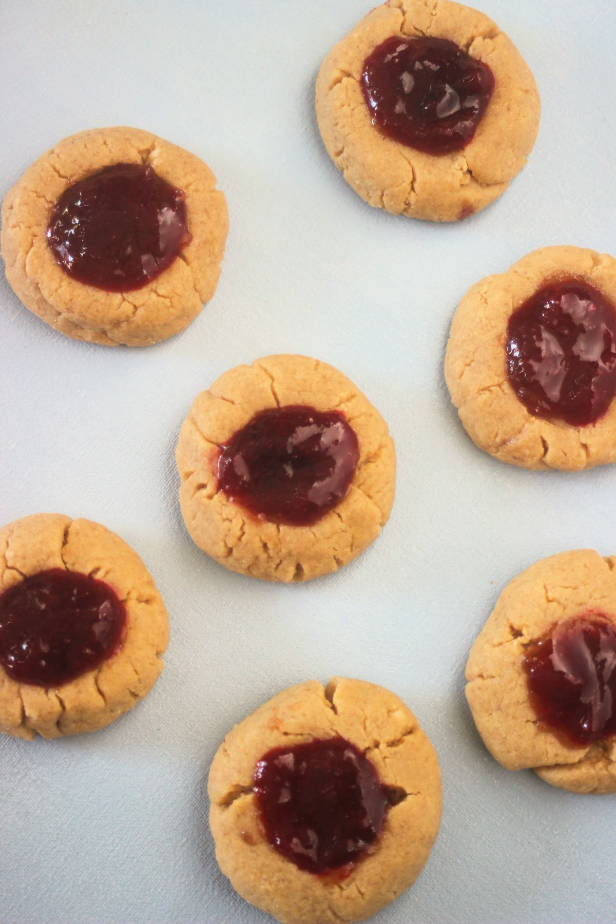 Top view of peanut butter thumbprint cookies on a white surface.