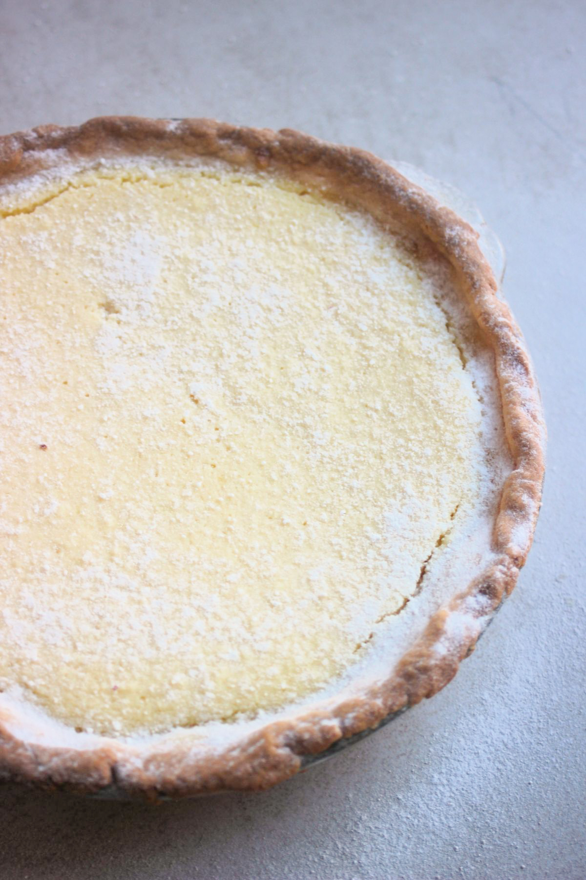 Partial view of ricotta pie dusted with powdered sugar.