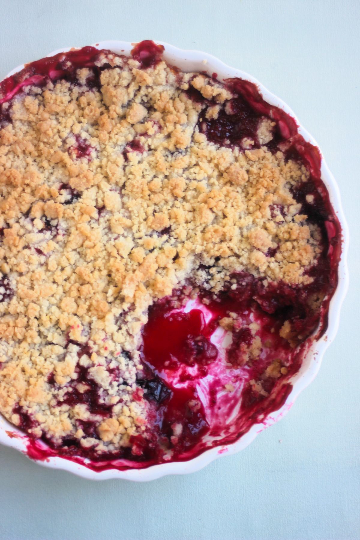 Top view of a round baking dish with plum crumble without a portion.