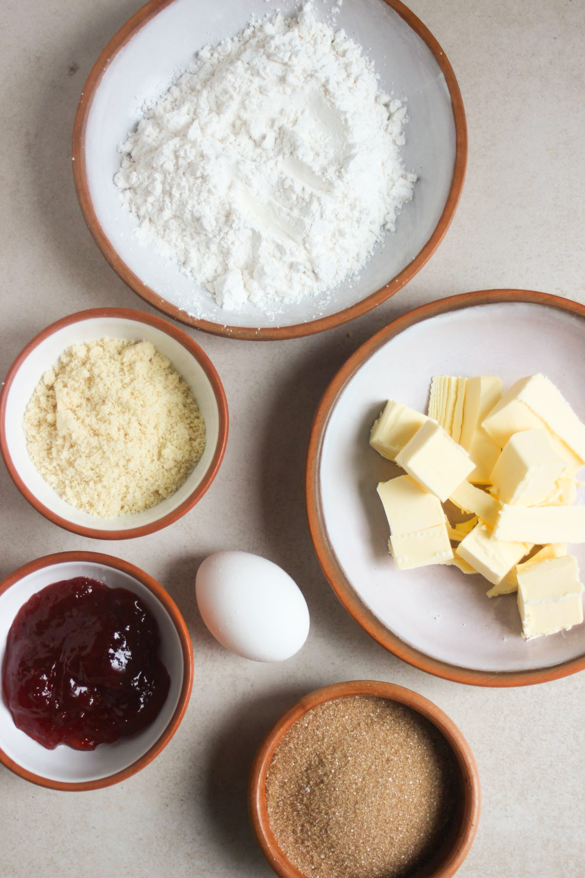 Top view of almond thumbprint cookies ingredients on a white surface.
