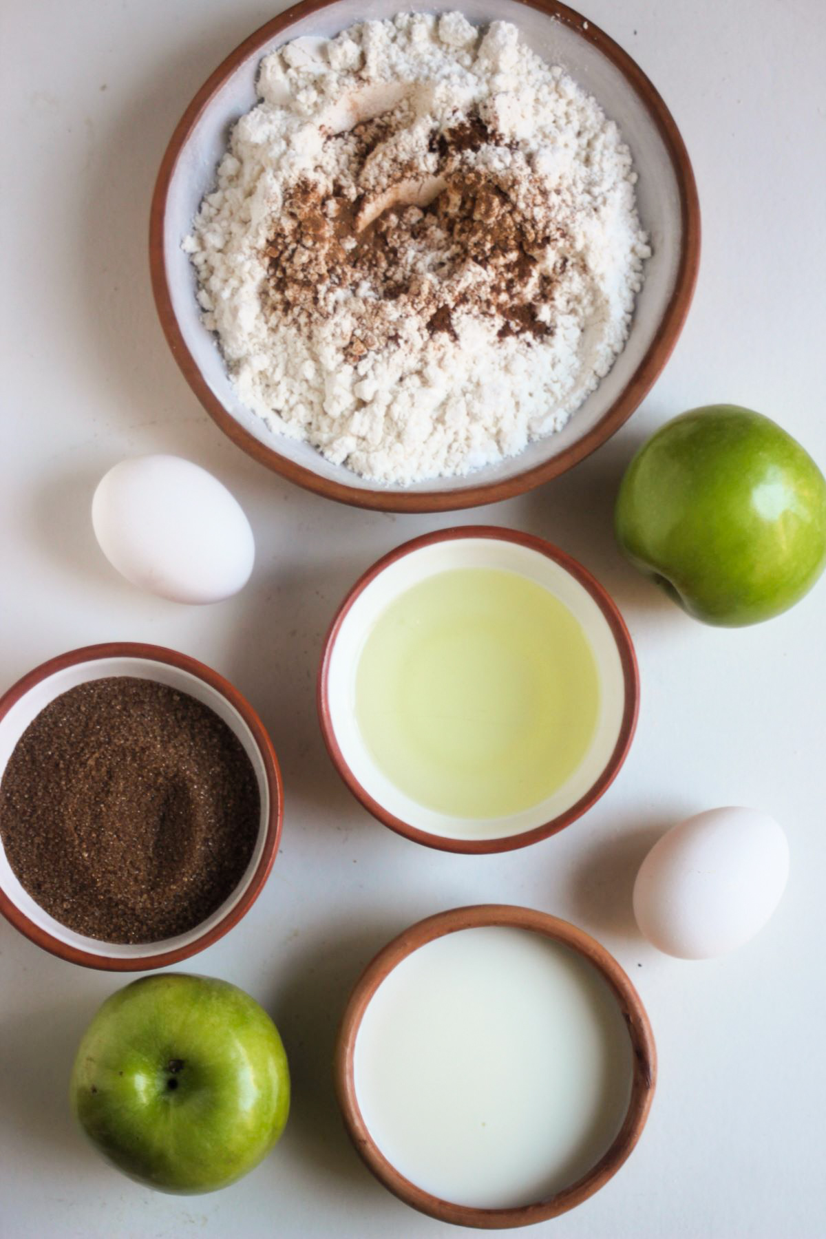 Apple crumb muffins ingredients on a white surface seen from above.