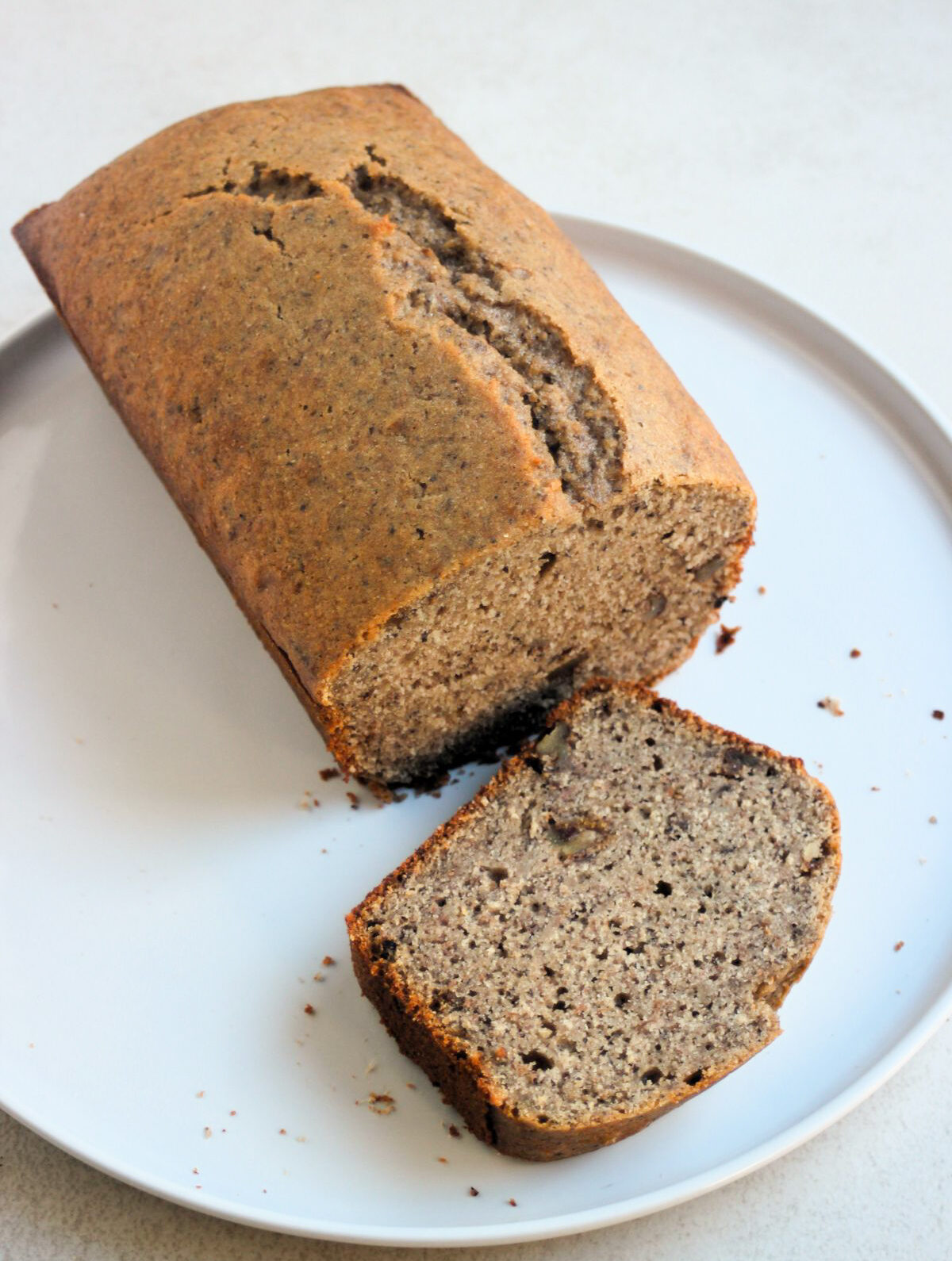 Banana loaf cake and a slice of it on a white plate.