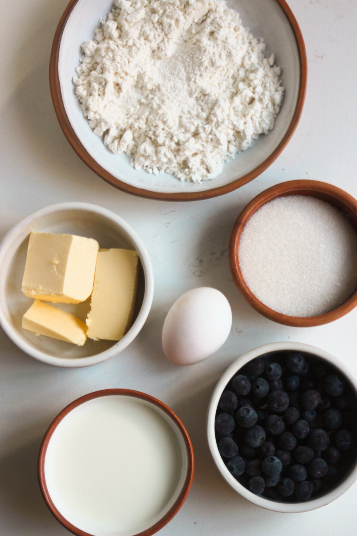 Blueberry scones ingredients on a white surface seen from above.