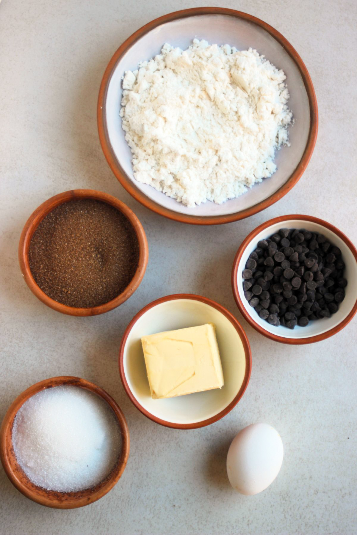 Chocolate chips cookies ingredients on a white surface seen from above.