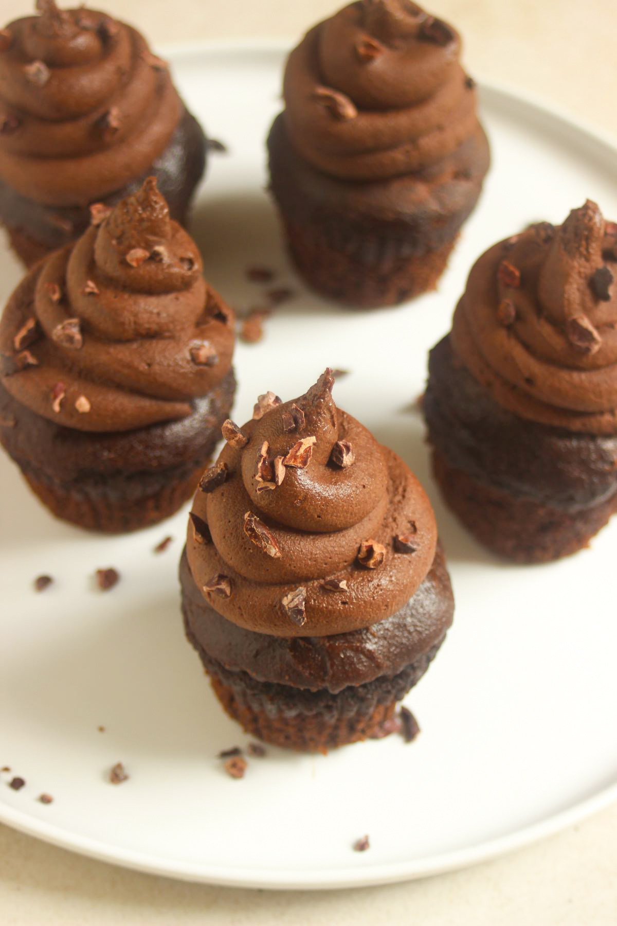 Chocolate cupacakes with cocoa nibs on a white plate.
