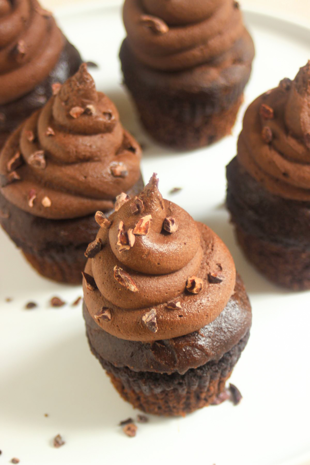 Chocolate cupacakes with cocoa nibs on a white plate.
