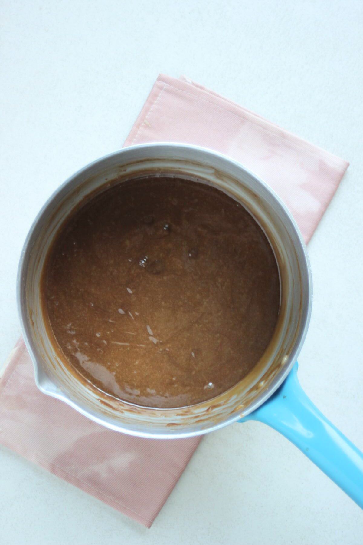 Deep saucepan with a chocolate mixture. Pink napkin under the saucepan.