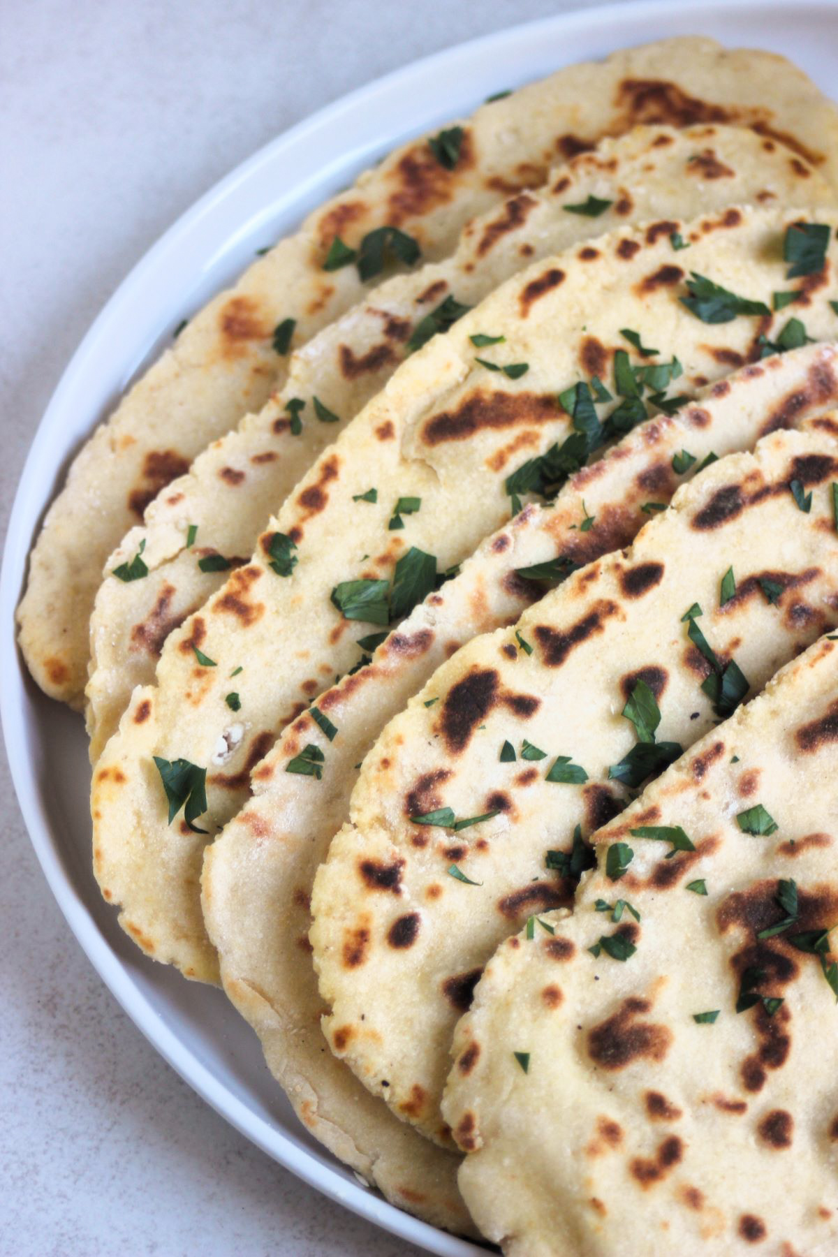 Flatbread plate with chopped fresh parsley on a white.
