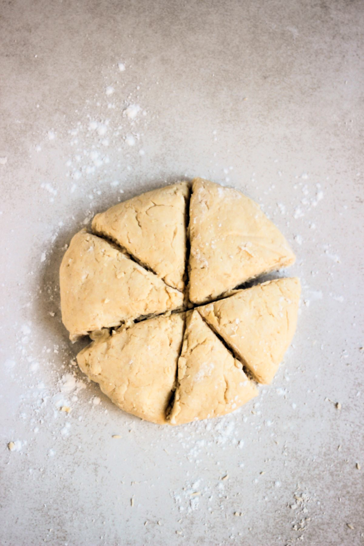 Flatbread dough stretched over a white surface.