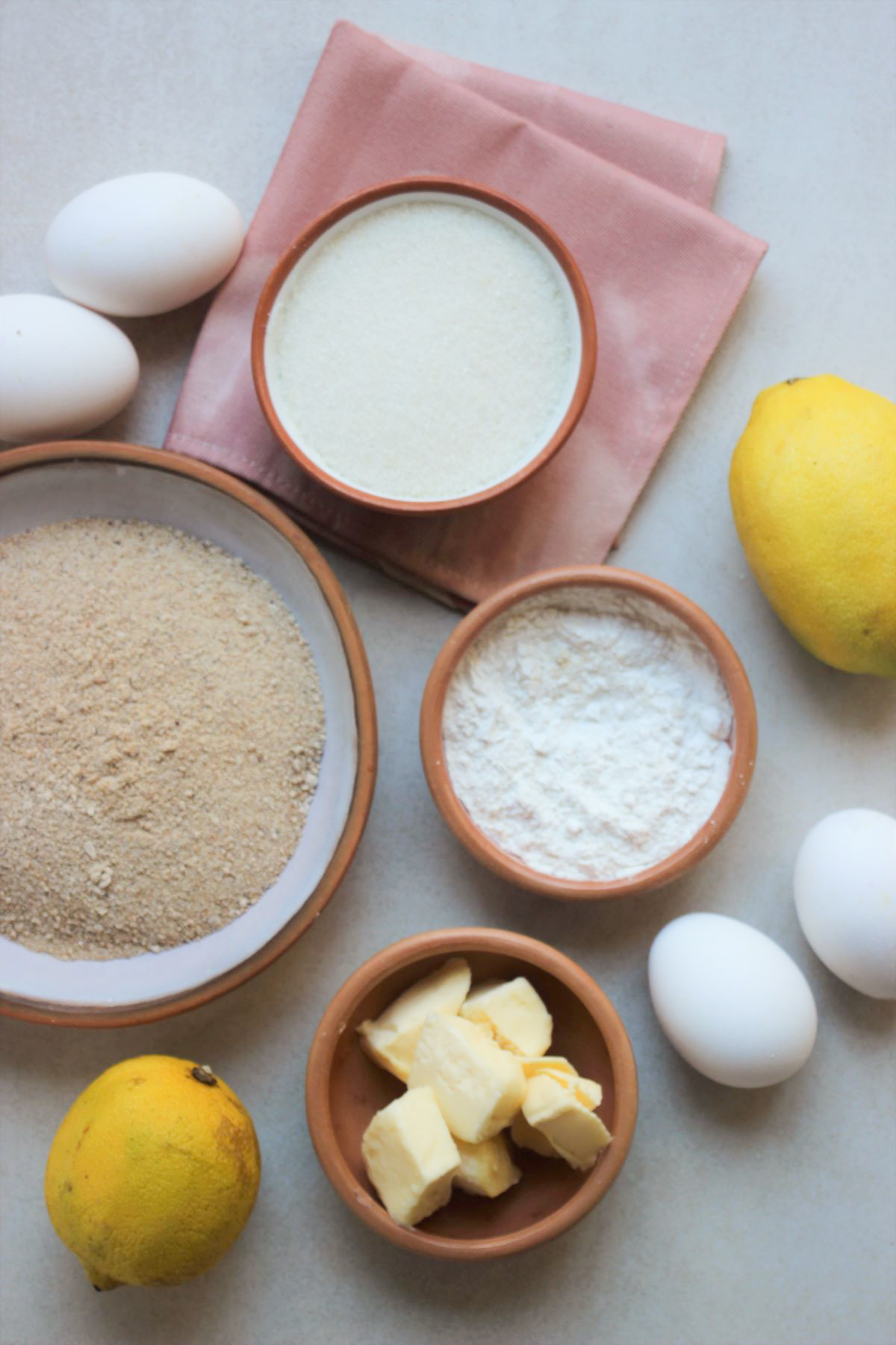 Lemon bars ingredients on a white surface seen from above.
