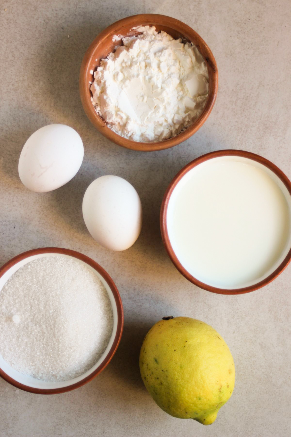 Lemon pudding cake ingredients on a white surface seen from above.
