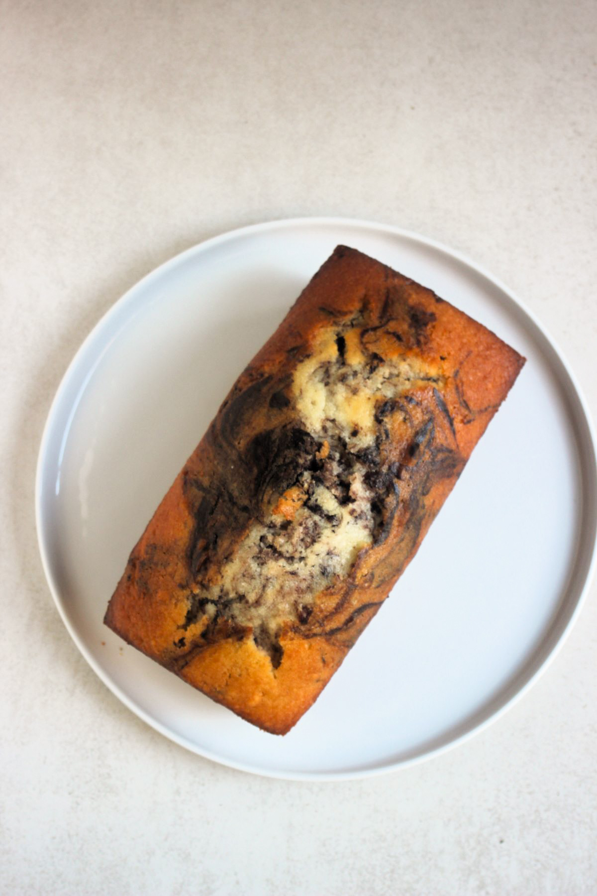 Marble loaf cake on a white plate seen form above.