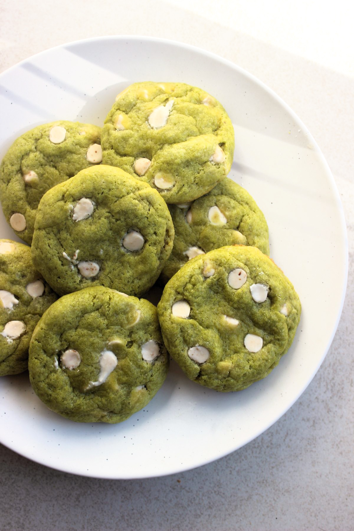 Matcha cookies with white chocolate chips on a white plate seen from above.