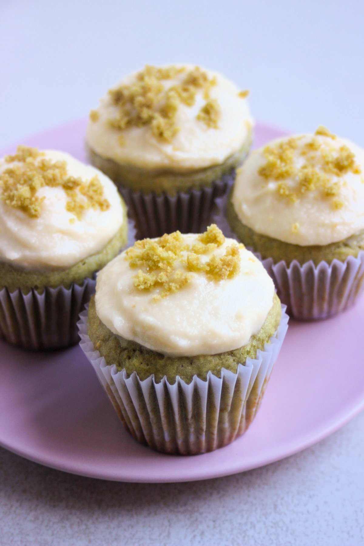 Matcha cupcakes with liners on a pink plate.