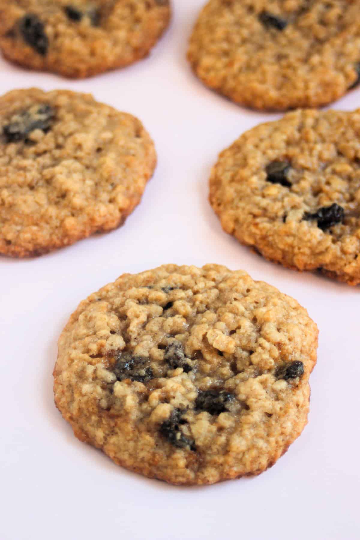 Oatmeal raisin cookies on a pink surface.