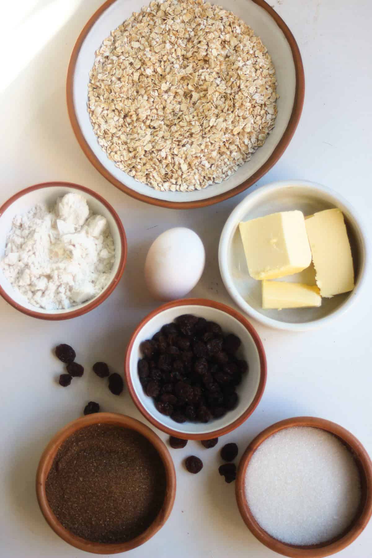 Oatmeal raisin cookies ingredients on a white surface seen from above.