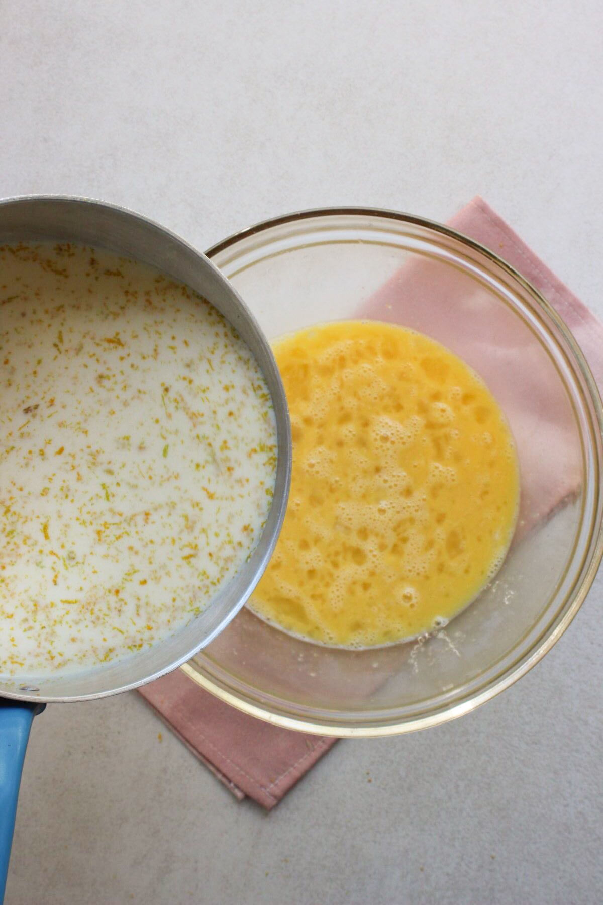 Deep Saucepan with milk is about to be poured into a bowl with eggs beaten.