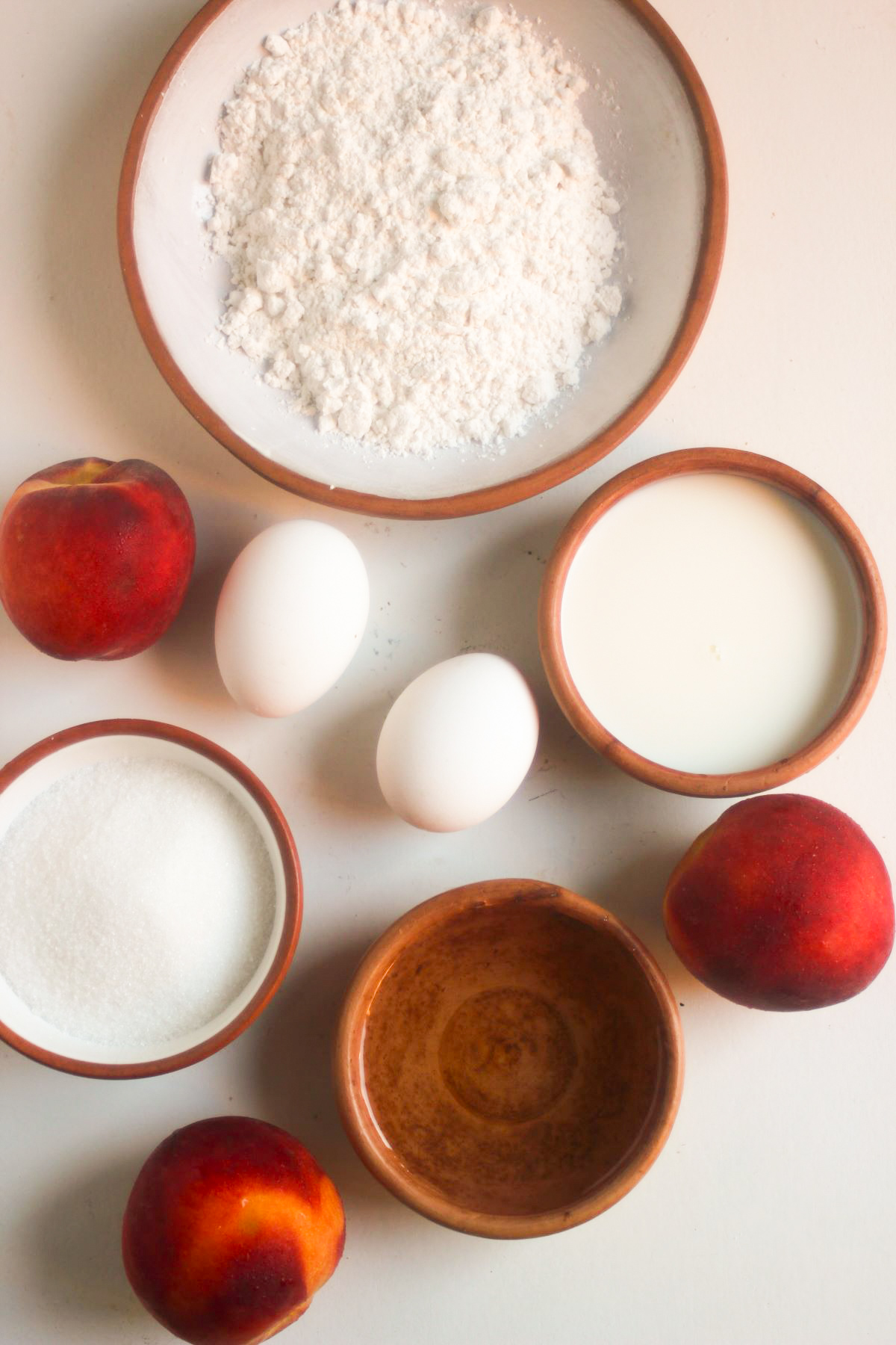 Fresh peach cake ingredients on a white surface seen from above.