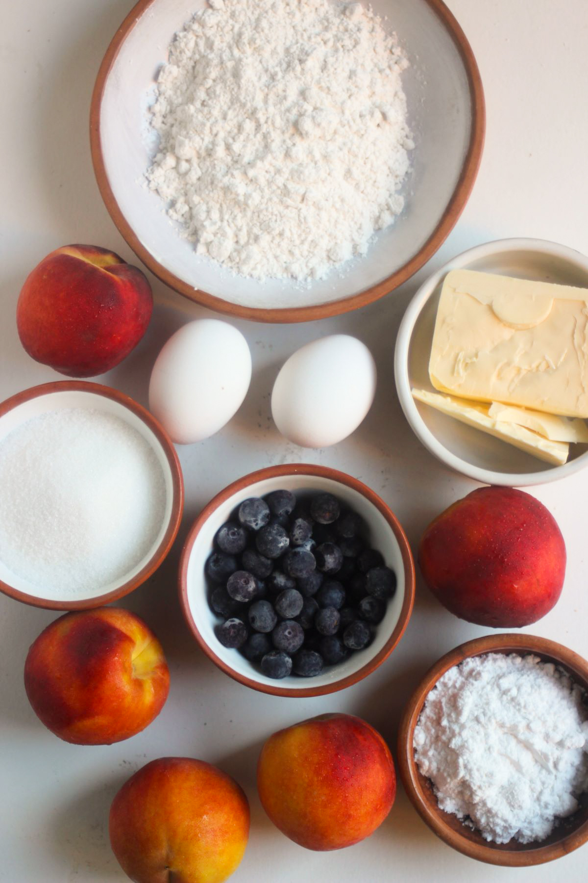 Top view of peach pie ingredients on a white surface.