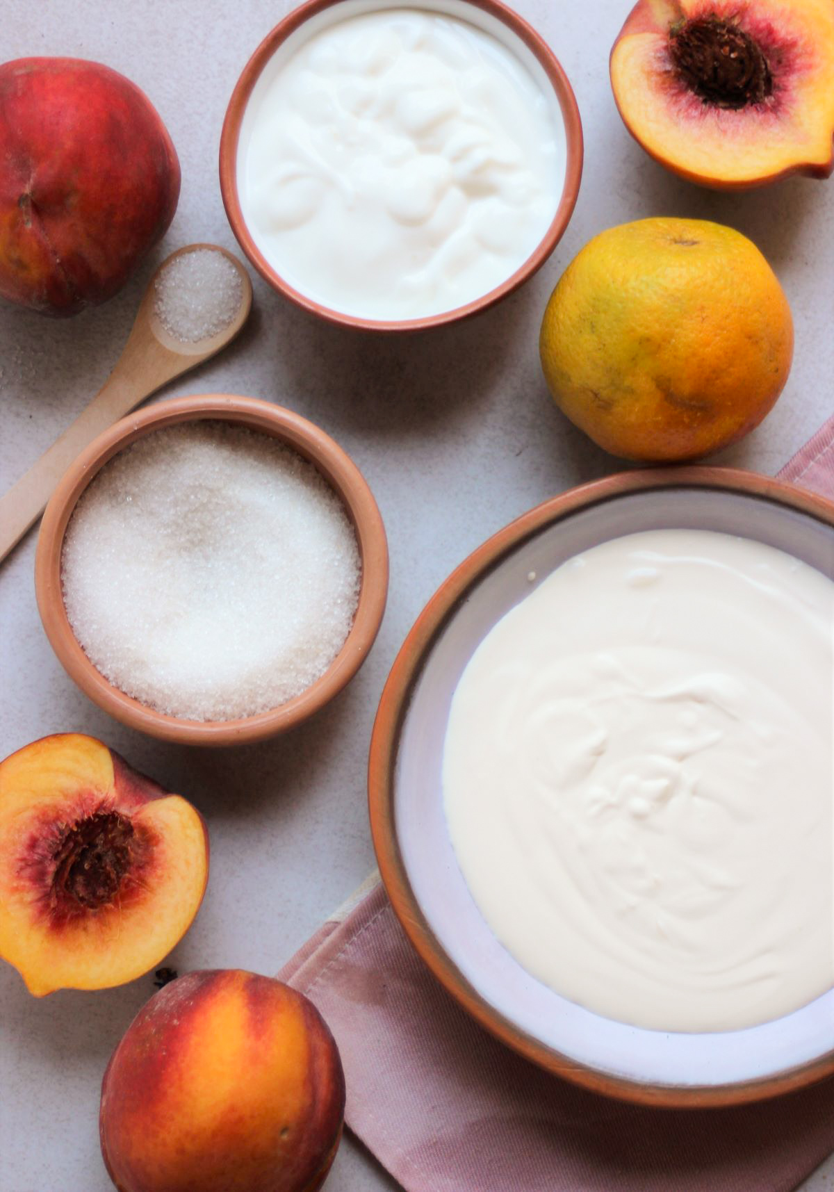 Peach yogurt trifle ingredients on a white surface seen from above.