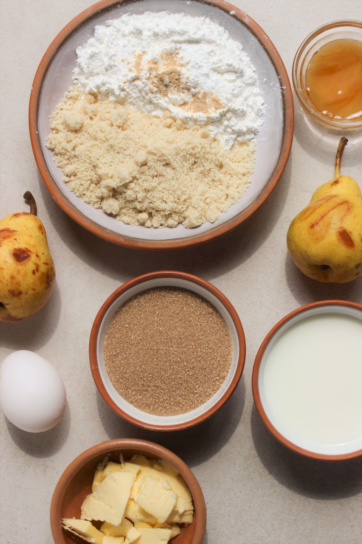 Pear and ginger muffins ingredients on a white surface seen from above.
