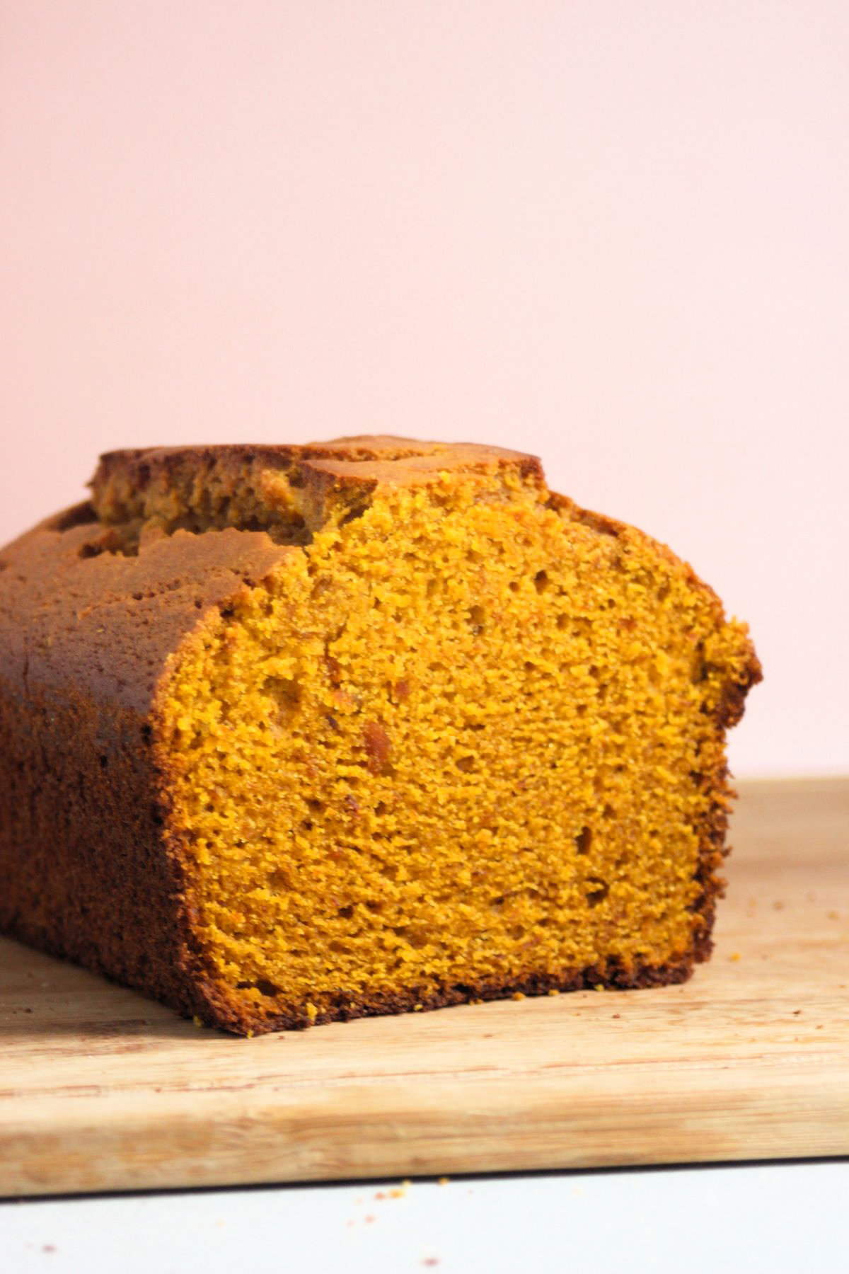 Pumpkin bread on a wooden table. Light pink background.