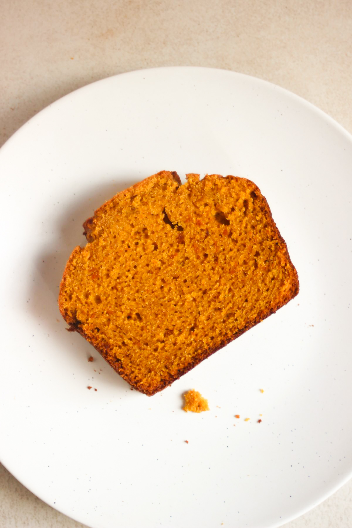 Top view of a pumpkin bread slice on a white plate.