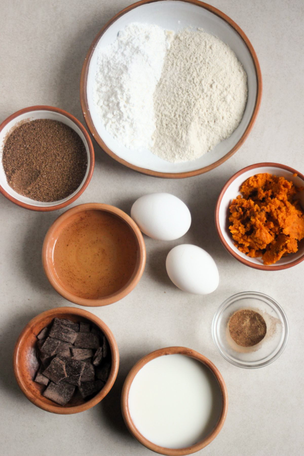 Pumpkin chocolate muffins ingredients on a white surface seen from above.