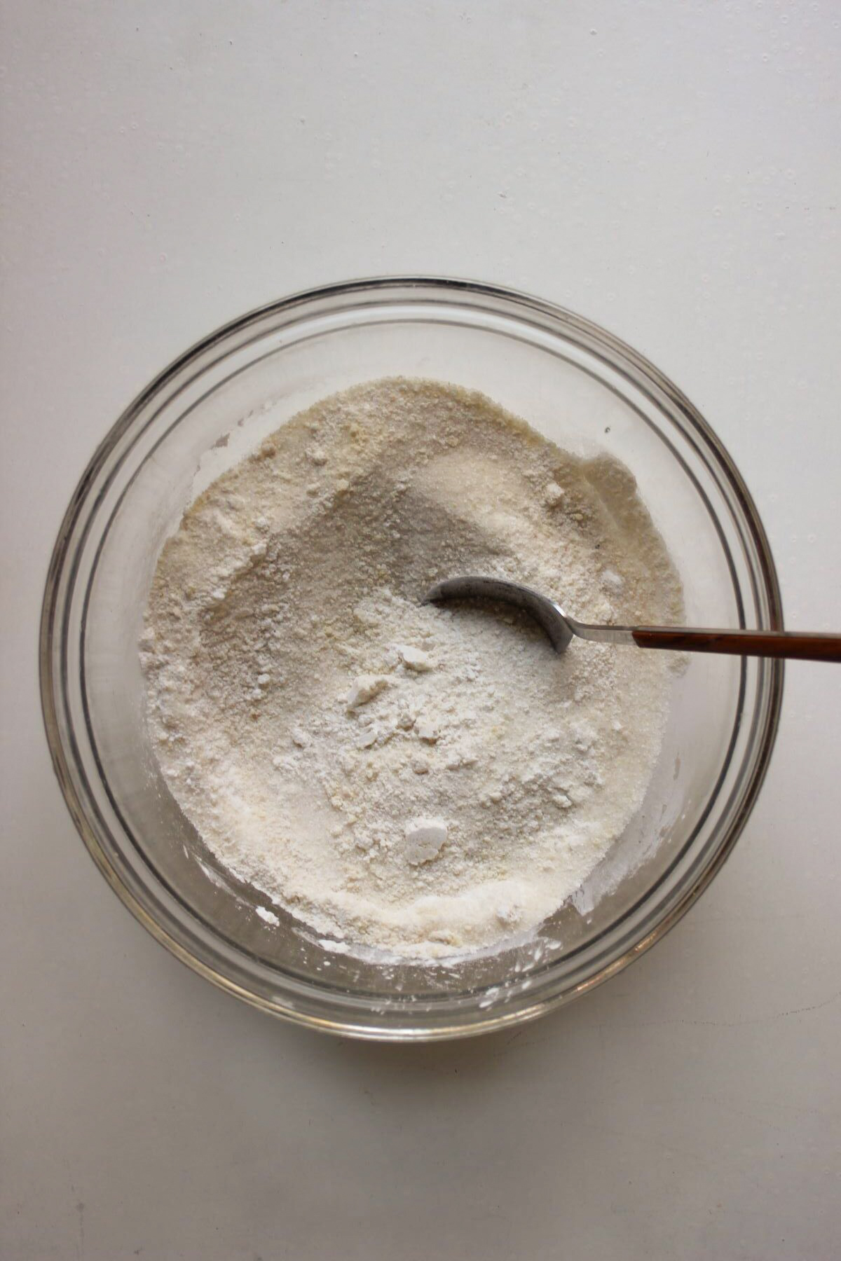 Glass bowl with a mix of flours and a spoon.