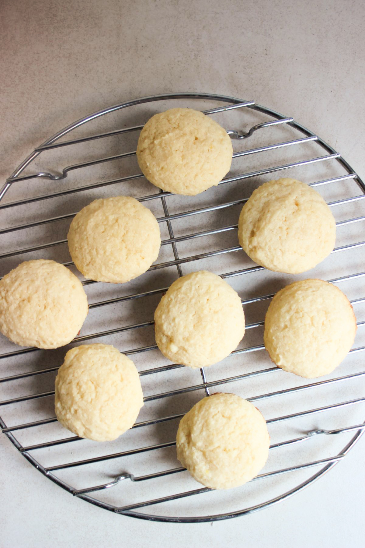 Ricotta cookies on a round wire rack seen from above.