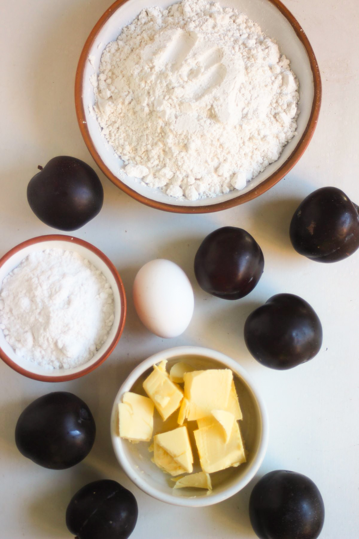 Rustic Plum Tart ingredients on a white surface seen from above.