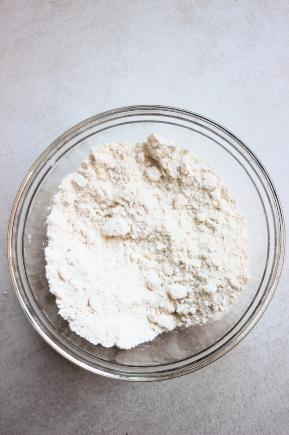 Glass bowl with flour on a white surface.