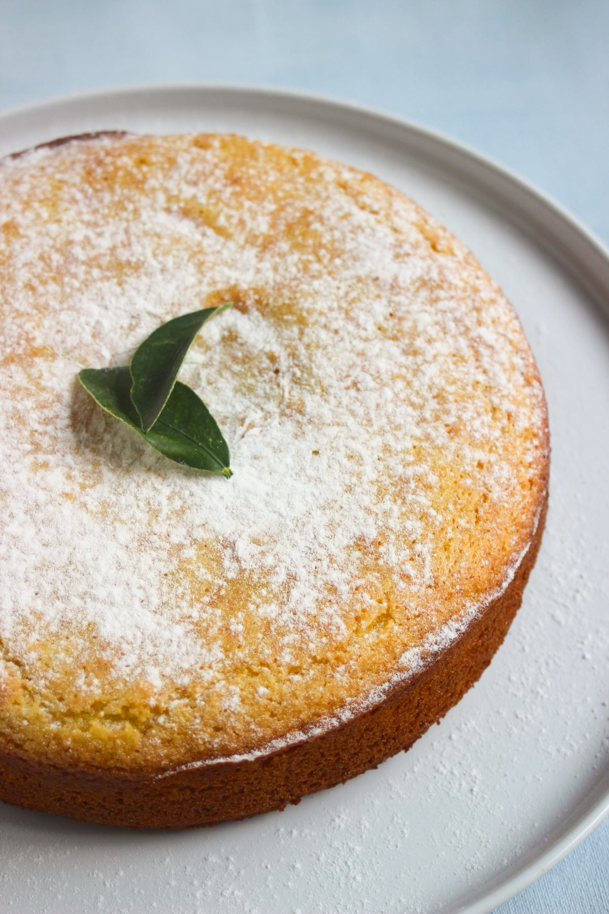 Whole orange cake on a white plate.