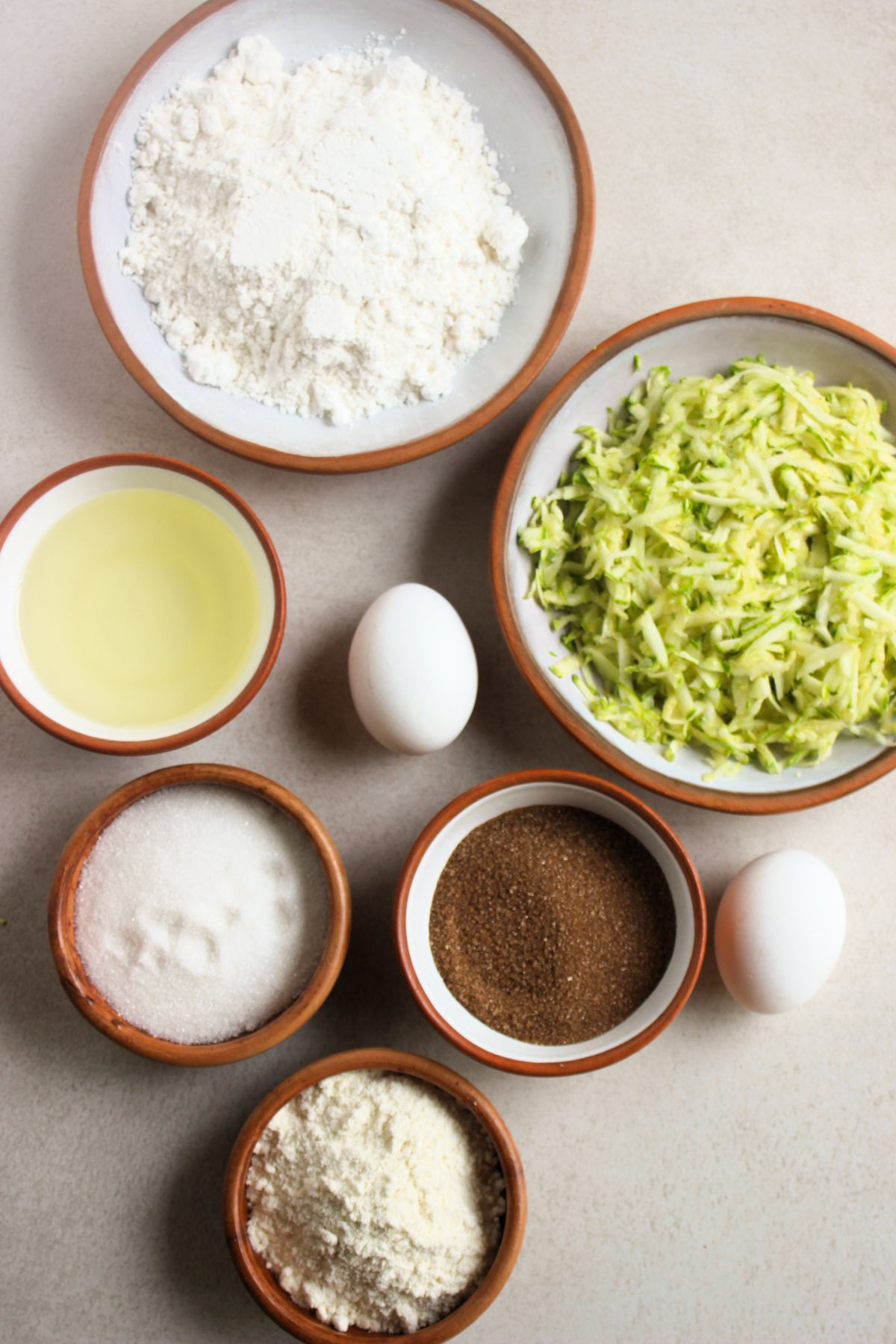 Top view of zucchini muffins ingredients on a white surface.