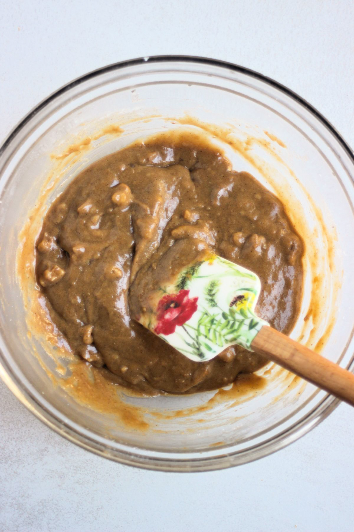 Glass bowl with sweet potato muffin batter and a rubber spatula.