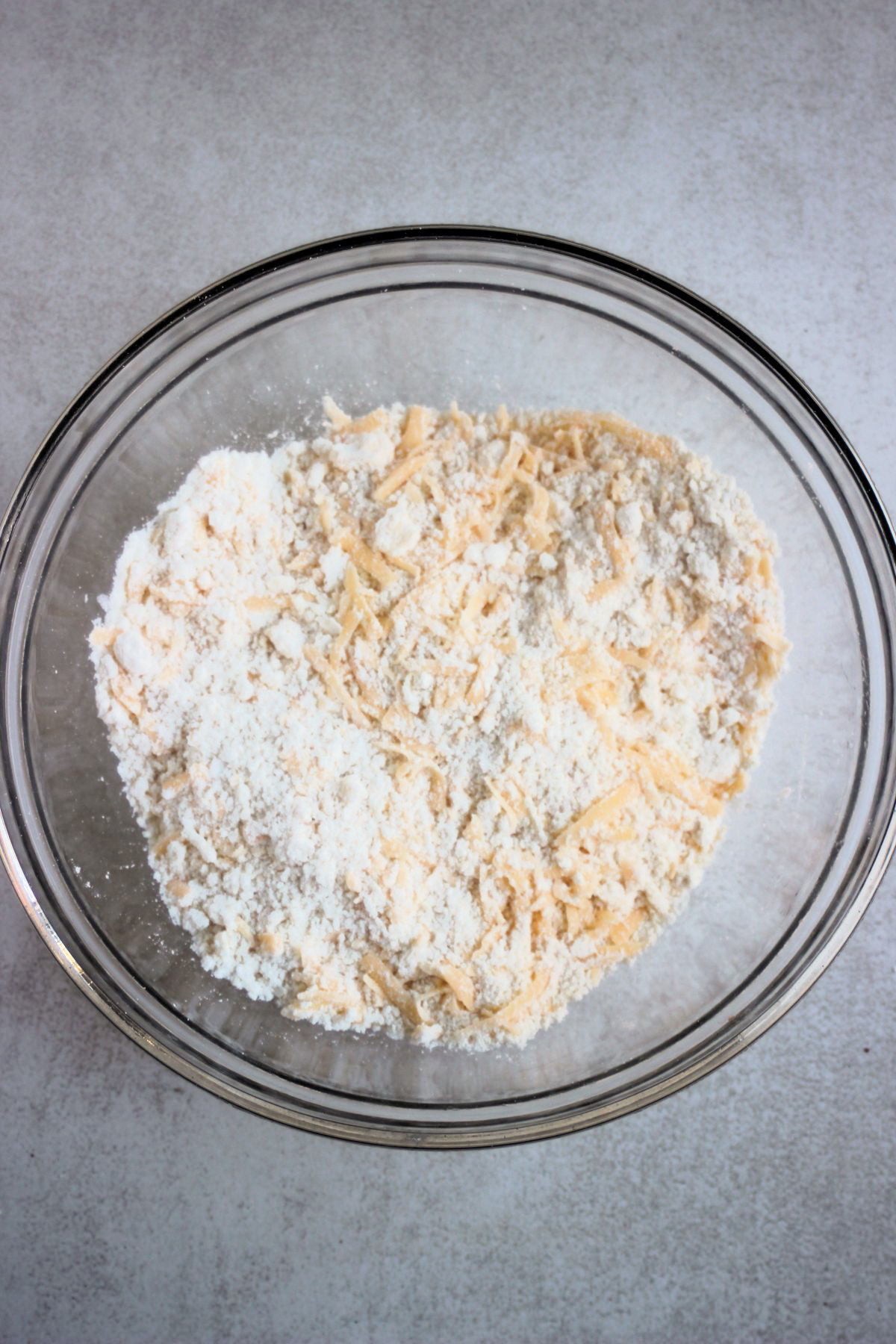 Bowl with a mixture that includes gluten-free all-purpose flour and shradded cheese.