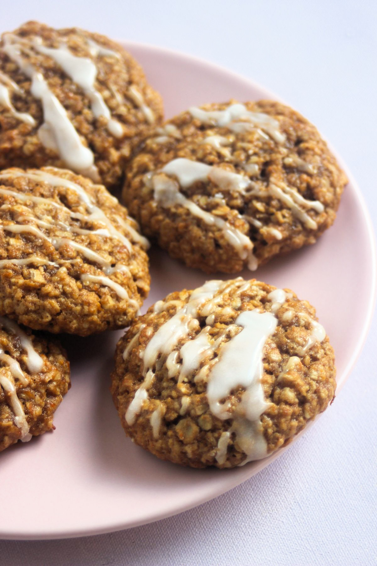 Pumpkin oatmeal cookies iced on a pink plate.