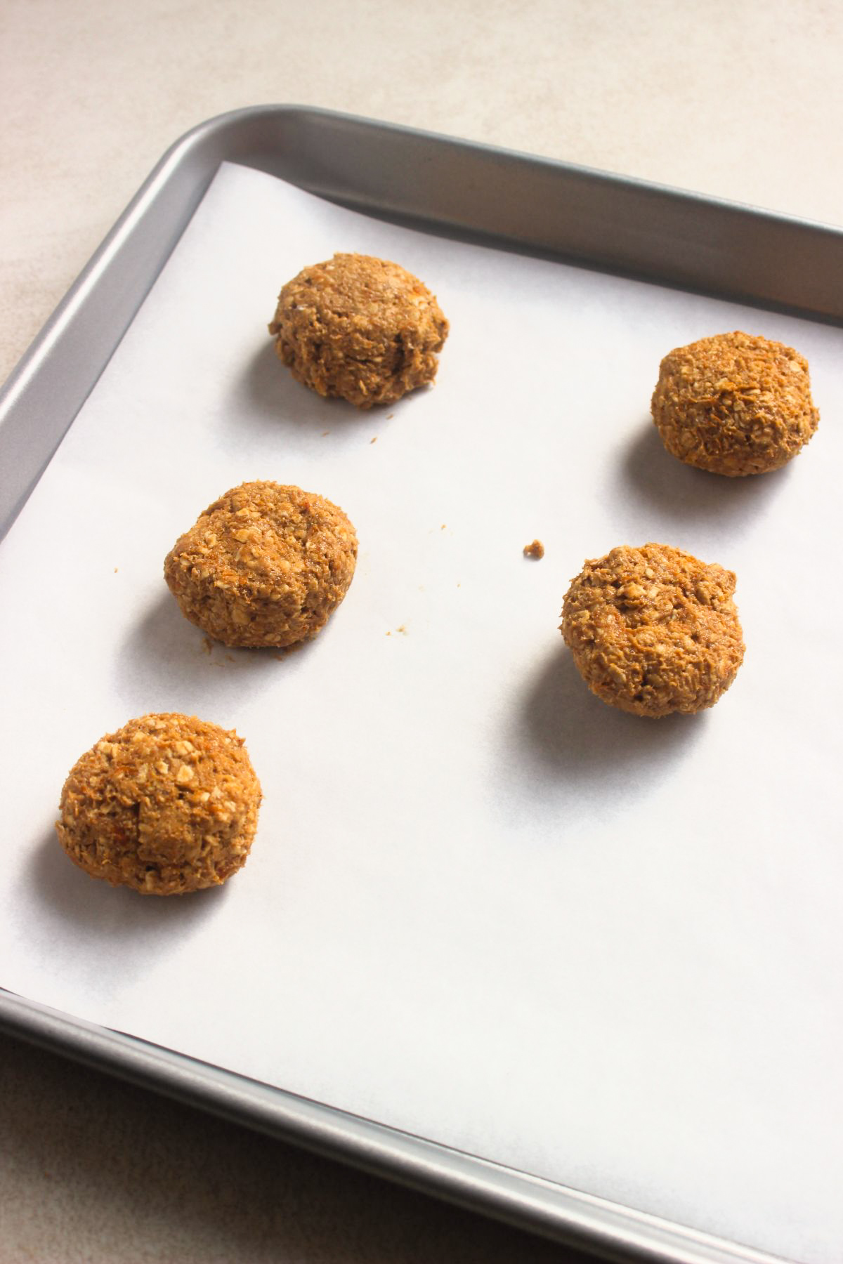 Cookie dough balls on a baking sheet with parchment paper.