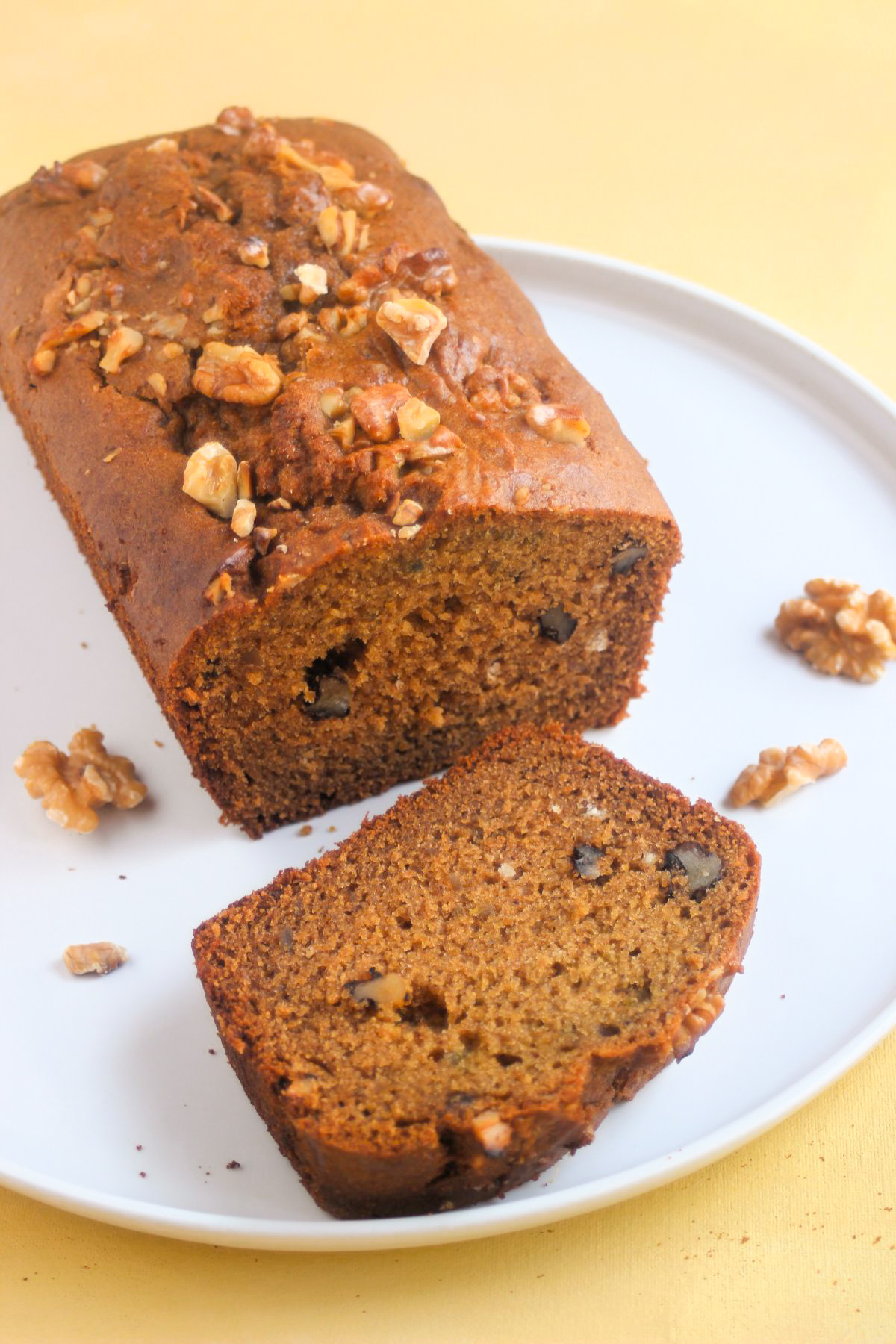 Sweet potato bread with walnuts and a slice of it on a white plate.