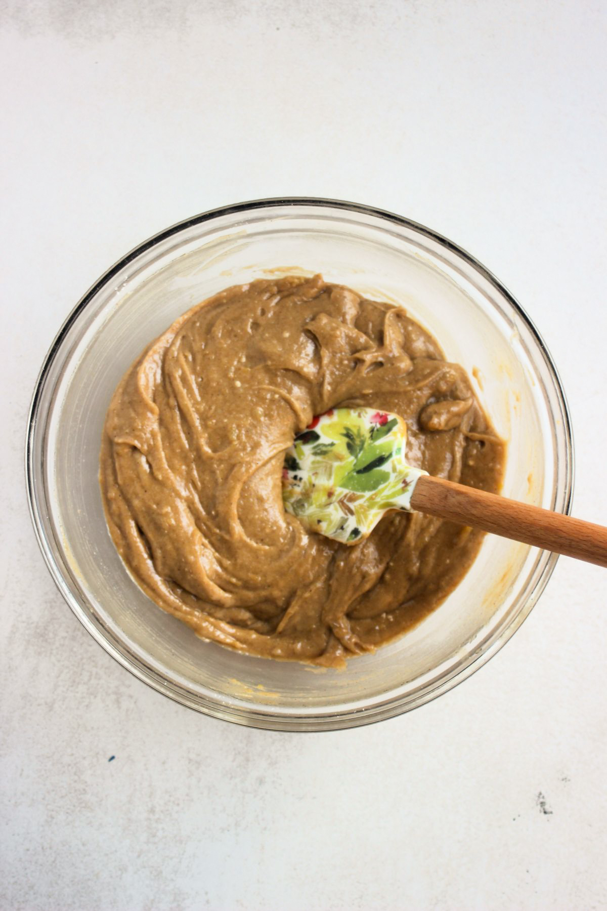 Glass bowl with sweet potato bread mixture and a rubber spatula.