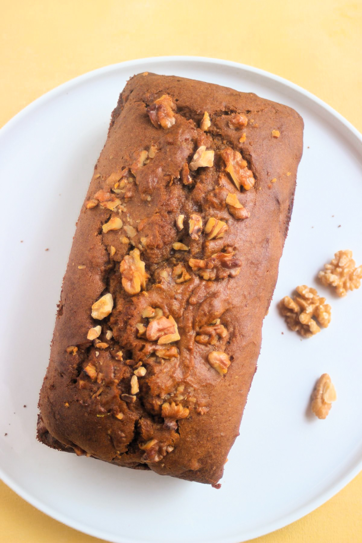 Top view of sweet potato bread with walnuts on a white plate.