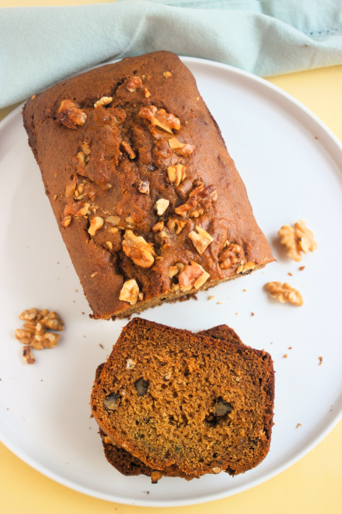 Top view of sweet potato bread with walnuts and two slice of it on a white plate.